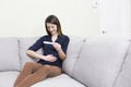 Girl sitting on a couch at home while reading the results of her recent pregnancy test Royalty Free Stock Photo