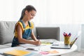 Girl sitting at desk, drawing in copybook