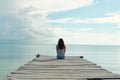 girl sitting at the end of a wooden pier, calm sea background Royalty Free Stock Photo