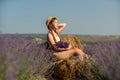 girl sitting field lavender and wearing a straw hat. She is smiling and holding a bouquet of flowers Royalty Free Stock Photo