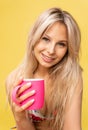 A girl sitting on the floor with her feet cross-legged keeps her head on a beautiful yellow background with a cup in Royalty Free Stock Photo