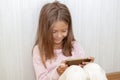 girl is sitting on the floor and playing mobile games on her phone. Concept of using a mobile phone by children for games and Royalty Free Stock Photo