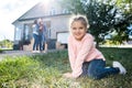 girl sitting in garded of new house while parents embracing Royalty Free Stock Photo