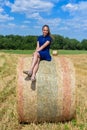 The girl is sitting on golden hay bales on the field Royalty Free Stock Photo