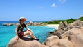 Girl sitting on granite stone near Anse Marron beach, La Digue Island, Indian ocean, Seychelles.