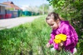 Girl sitting on grass and collecting blooming yellow dandelion flowers Royalty Free Stock Photo