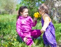 Girl sitting on grass and giving to smell dandelion flowers to small boy Royalty Free Stock Photo