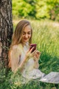 girl sitting on the grass looking at the phone. freelance. selfeducation. the concept of remote learning and outdoor