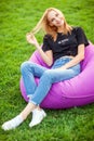 Girl sitting on grass in park on chair bag