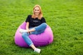 Girl sitting on grass in park on chair bag