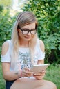 The girl sitting on the grass with tablet in hands