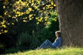 Girl sitting on the grass under maple tree in autumn Royalty Free Stock Photo