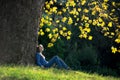 Girl sitting on the grass under maple tree in autumn Royalty Free Stock Photo