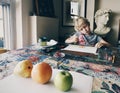 Girl sitting in home art studio concentrated on painting fruits with brushes and watercolor paints Royalty Free Stock Photo