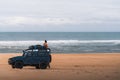 Girl sitting on Land Rover 4WD with camping equiptment parked on stockton beach, Newcastle, NSW.