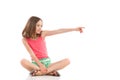 Girl sitting with legs crossed and pointing Royalty Free Stock Photo