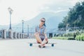 Girl sitting on longboard outdoor.