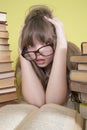 Girl sitting with lots of books and grabs his head. Royalty Free Stock Photo