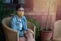 Girl sitting with a mask on a straw chair to rest on the terrace with a copy space in the photograph