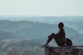 Girl sitting n the hill and looks into the distance of the forest. Haze