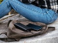 The girl is sitting in nature and waiting for the smartphone to charge from the power Bank. The concept of using modern Royalty Free Stock Photo