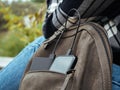 The girl is sitting in nature and waiting for the smartphone to charge from the power Bank. The concept of using modern Royalty Free Stock Photo