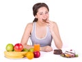 Girl sitting near fruit and sweets and bites chocolate Royalty Free Stock Photo