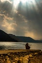 Girl sitting near lake shore at day Royalty Free Stock Photo