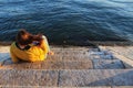 Girl sitting next to the riverbank at sunset in Lisbon