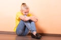 Girl sitting offended on the floor, light orange background Royalty Free Stock Photo