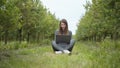 Girl sitting in park or forest, opening laptop on nature. IT specialist working at self isolation outdoors. Women
