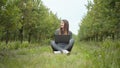 Girl sitting in park or forest, opening laptop on nature. IT specialist working at self isolation outdoors. Women