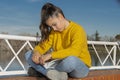 Girl sitting in a park reading a book in a yellow sweater