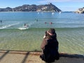 A girl sitting on the pier of Donostia-San Sebastian, Basque Country, City, Spain. The beach of La Concha panoramic view