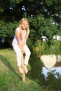 Girl sitting on pillar by a river