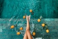 Girl sitting by pool with floating pineapples in blue clear water.