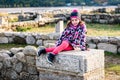 Girl is sitting on remains of ancient roman ruins stone