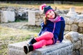 Girl is sitting on remains of ancient roman ruins stone