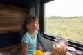 Girl sitting in a reserved seat wagon looks tiredly out the window Royalty Free Stock Photo