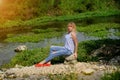 A girl sitting on the river bank in silence