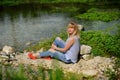 A girl sitting on the river bank in silence