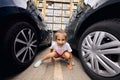 A girl is sitting on the road markings in the parking lot between two cars Royalty Free Stock Photo