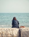 Girl sitting on a rock on the beach of the Black Sea and looking at the horizon Royalty Free Stock Photo