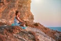 Girl sitting on rock and enjoying nature. Sunset and fresh air. Self absorbed and contemplation time idea, copy space
