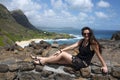 A girl sitting on a rocks a front of the ocean bay