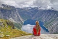 Girl sitting on rock and looking at Norwegian mountain landscape. Trail to Trolltunga rock. Ringedalsvatnet lake, Norway Royalty Free Stock Photo