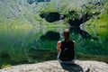 A girl sitting on a rock, looking at a spectacular view of the mountain reflecting in the lake. Royalty Free Stock Photo