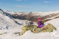 Girl sitting on a rock at snowy mountains