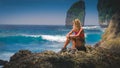 Girl sitting on the Rock and watching Huge Waves hitting Tembeling Coastline at Nusa Penida Island, Bali Indonesia Royalty Free Stock Photo