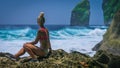 Girl sitting on the Rock and watching Huge Waves hitting Tembeling Coastline at Nusa Penida Island, Bali Indonesia Royalty Free Stock Photo